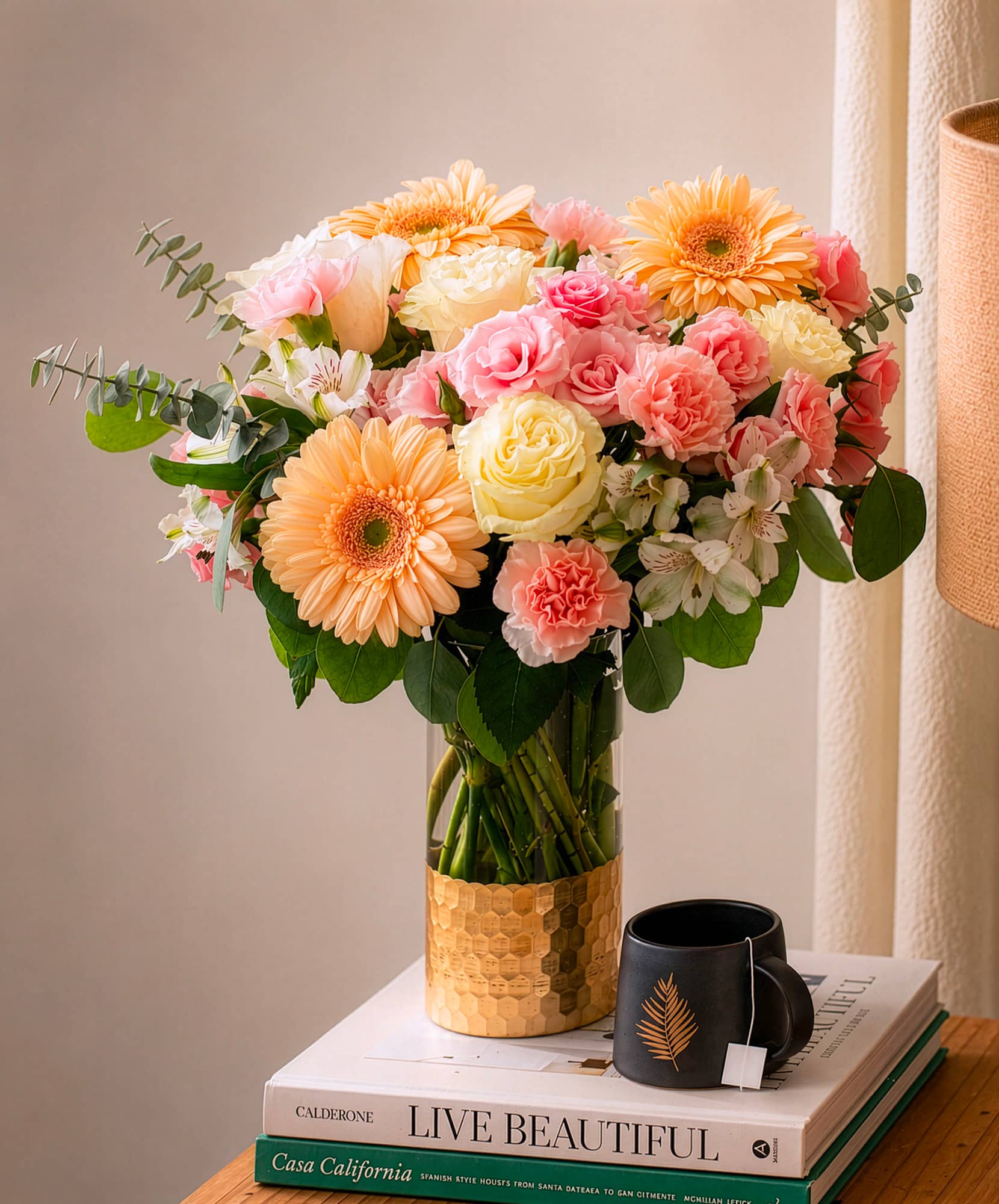 A vibrant floral arrangement featuring gerbera daisies, roses, and greens in a chic vase.